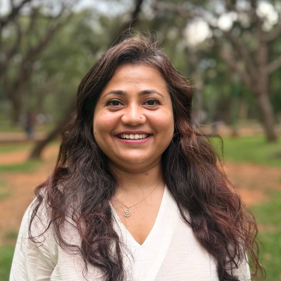 Shikha, smiling, photographed outdoors among trees